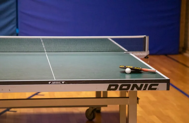 Sto za stoni tenis sa reketom i lopticom u sali